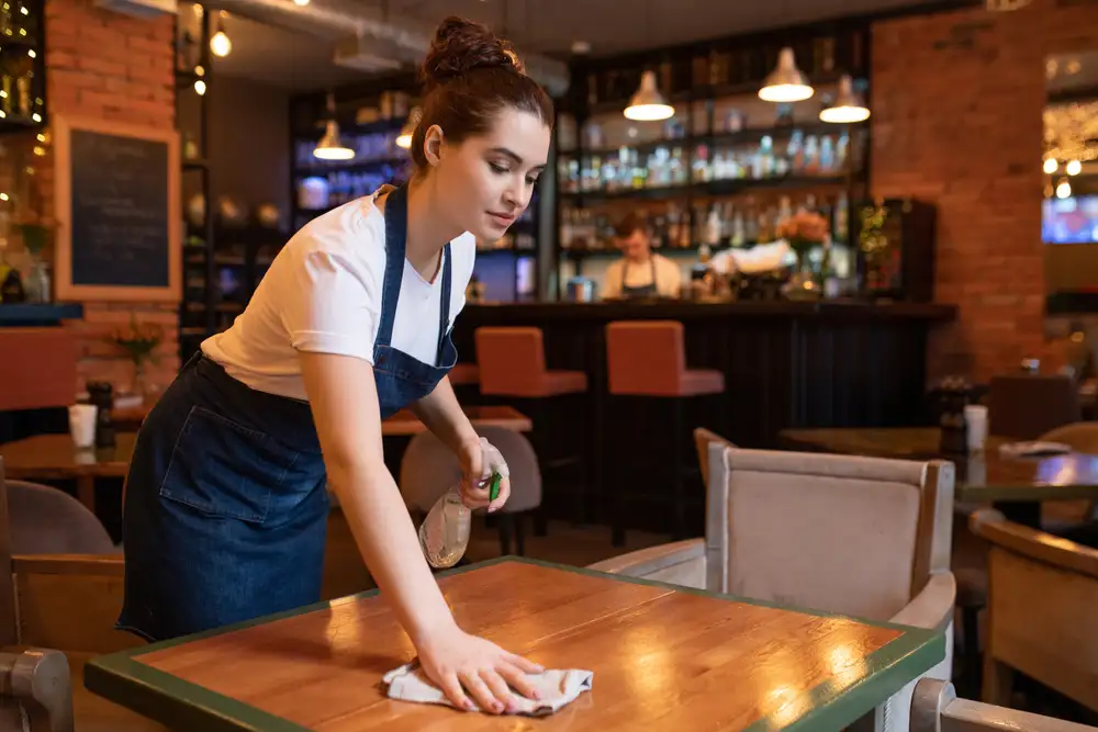 Restaurant reservations system can help a restaurant with managing booking and allows the restaurant manager to schedule the right number of staff, prep ingredients based on demand, and manage orders more accurately. This image shows an additional staff member preparing a table for a couple that made their reservation through a restaurant reservations system.