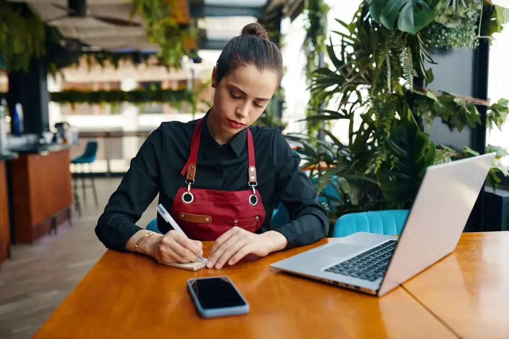 Staff can be trained to use a restaurant reservation system like OpenTable to manage reservations, view guest history, and handle walk-ins. This image shows a restaurant staff member using a tablet to review the restaurant's online reservation system.